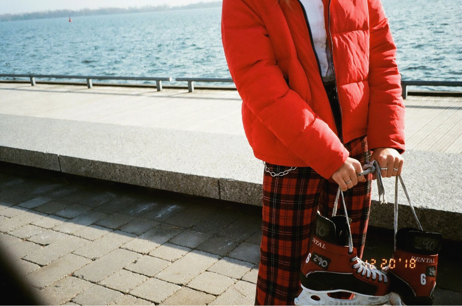Aubrey holding a pair of hockey skates in front of the water. Shot on 35mm film. 