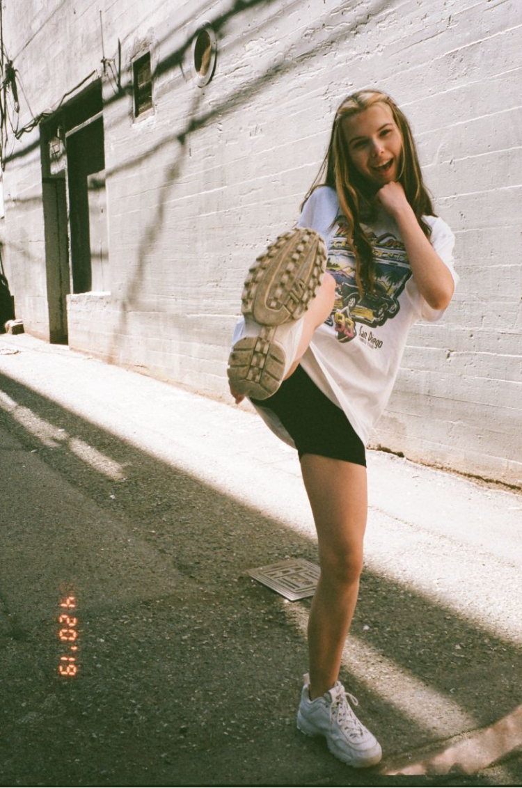 A girl pretending to kick the camera in an alleyway. Shot on 35mm film.