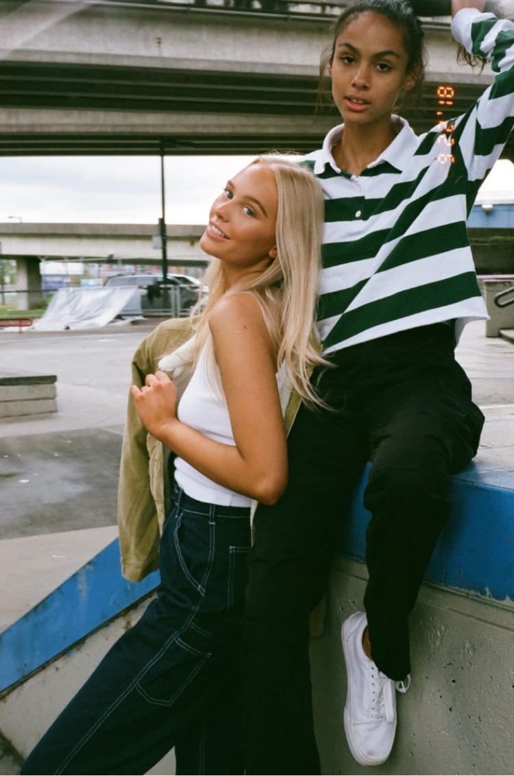 Two girls posing while sitting on the ledge of a skate ramp. Shot on 35mm film. 