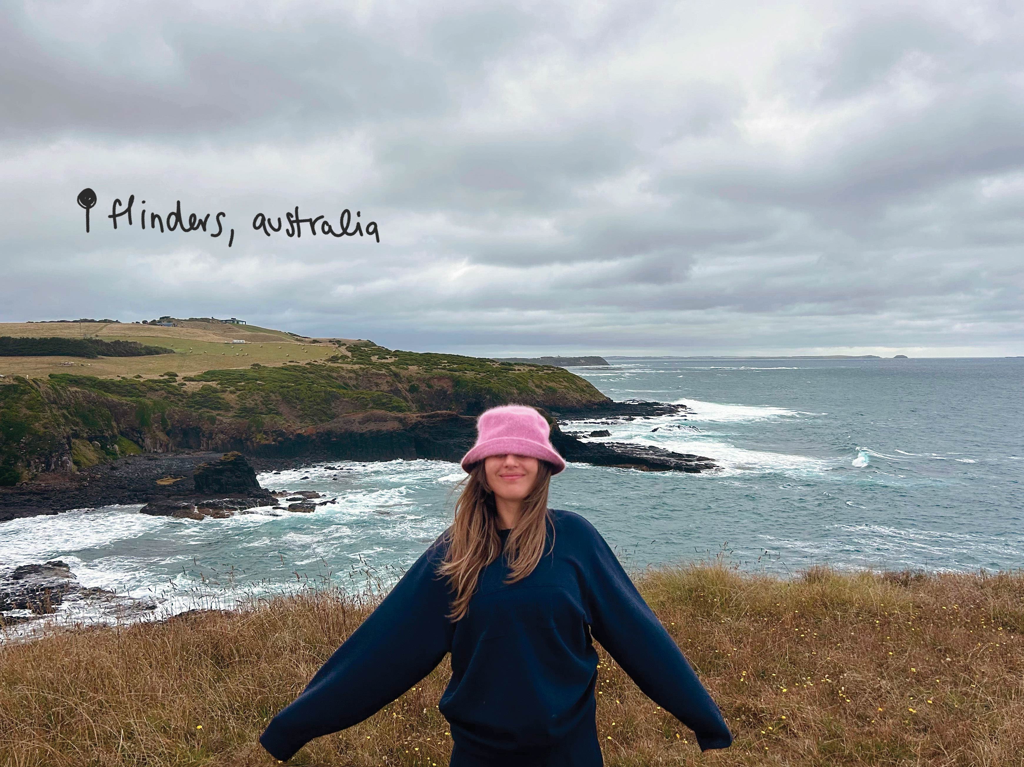 Aprille on a beach holding a film camera, taking a photo.